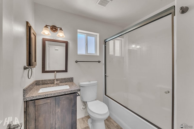 bathroom with toilet, visible vents, combined bath / shower with glass door, and vanity