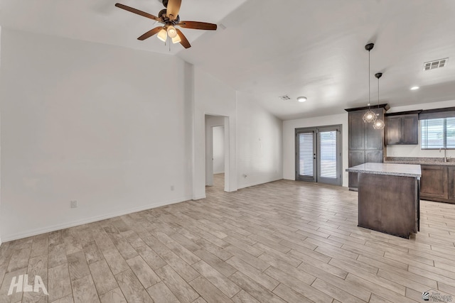 kitchen with open floor plan, light wood finished floors, a kitchen island, and visible vents