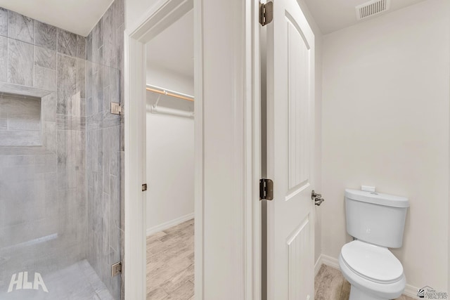 full bath with visible vents, a spacious closet, toilet, a stall shower, and baseboards