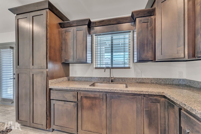 kitchen featuring dark brown cabinets, light countertops, and a sink