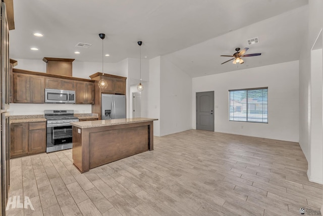 kitchen featuring visible vents, a kitchen island, appliances with stainless steel finishes, open floor plan, and light wood-style floors