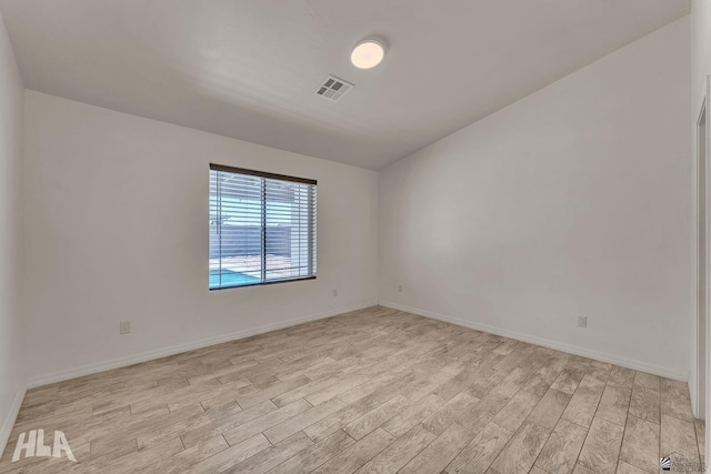 empty room featuring light wood-style floors, baseboards, and visible vents