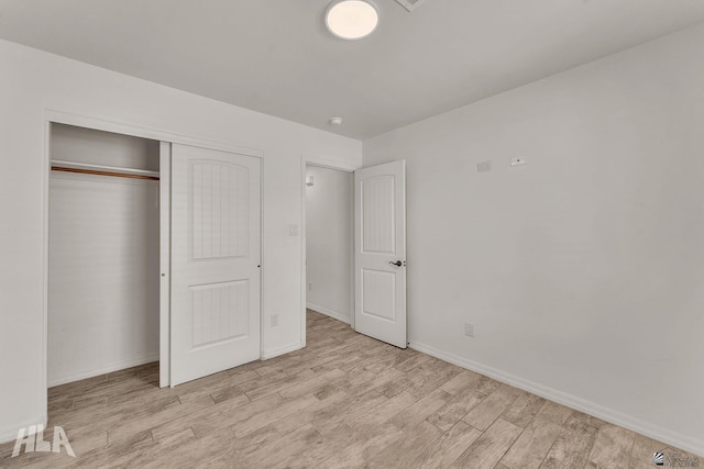 unfurnished bedroom with a closet, light wood-type flooring, and baseboards