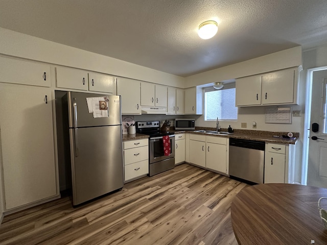 2240 S Elks Ln # 21, Yuma, AZ 85364 - kitchen with stainless steel appliances, a sink, dark countertops, light wood-style floors, and a textured ceiling