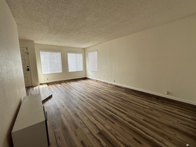 2240 S Elks Ln # 21, Yuma, AZ 85364 - unfurnished room featuring a textured ceiling, dark wood-style floors, baseboards, and a textured wall