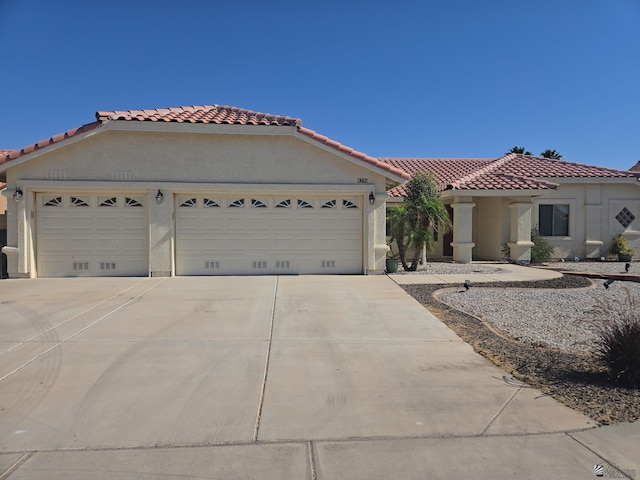 mediterranean / spanish house featuring a garage, driveway, a tile roof, and stucco siding