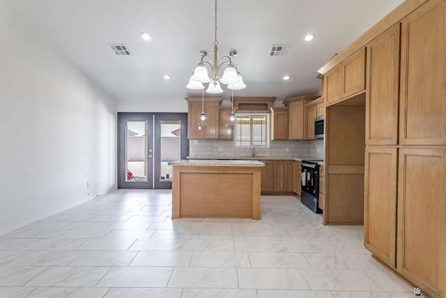 10849 E 45th Pl, Yuma, AZ 85367 - kitchen with black range with electric cooktop, stainless steel microwave, a chandelier, a center island, and decorative backsplash