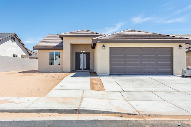 10849 E 45th Pl, Yuma, AZ 85367 - prairie-style house with stucco siding, concrete driveway, a garage, a tile roof, and french doors