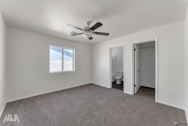 1124 N Villareal Ave, San Luis, AZ 85336 - unfurnished bedroom with dark colored carpet, baseboards, a walk in closet, a ceiling fan, and ensuite bath