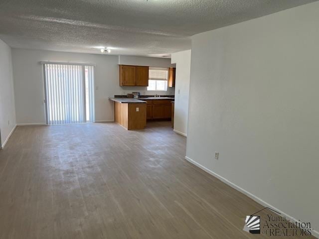 kitchen with open floor plan, baseboards, wood finished floors, and brown cabinets