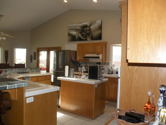 10224 S Fairway Ln, Yuma, AZ 85367 - kitchen with a kitchen island with sink, tile countertops, under cabinet range hood, a ceiling fan, and light tile patterned flooring