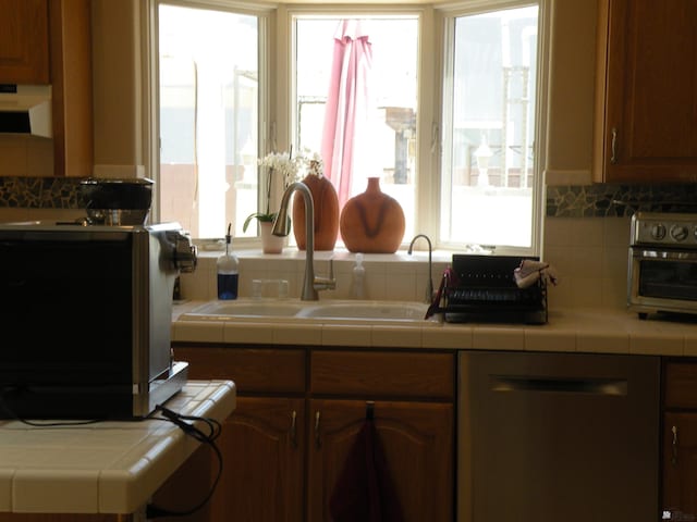 10224 S Fairway Ln, Yuma, AZ 85367 - kitchen featuring stainless steel dishwasher, a sink, tile counters, tasteful backsplash, and exhaust hood