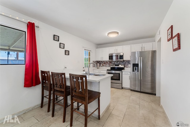 2605 S Nogales Ave, Yuma, AZ 85364 - kitchen featuring appliances with stainless steel finishes, light countertops, white cabinetry, a kitchen bar, and backsplash