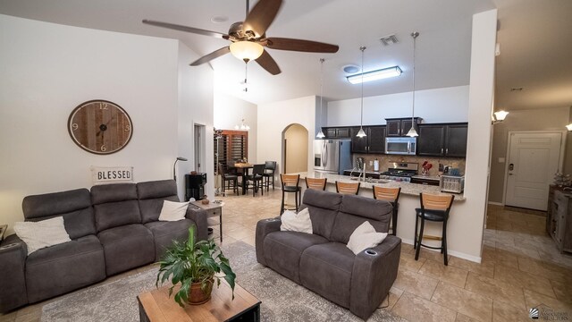 living area with visible vents, a ceiling fan, light tile patterned flooring, high vaulted ceiling, and arched walkways