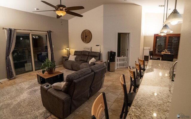 living room with ceiling fan, visible vents, light tile patterned floors, high vaulted ceiling, and baseboards