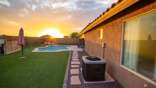 yard at dusk featuring a fenced backyard, a fenced in pool, and central AC unit