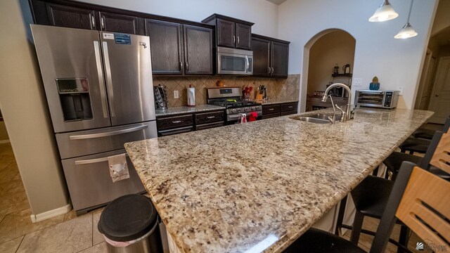 kitchen with a sink, arched walkways, a kitchen breakfast bar, and stainless steel appliances
