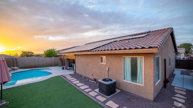 back of property featuring roof mounted solar panels, a fenced in pool, stucco siding, and a fenced backyard