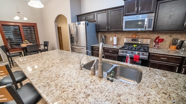 kitchen featuring a breakfast bar, arched walkways, tasteful backsplash, a sink, and stainless steel appliances