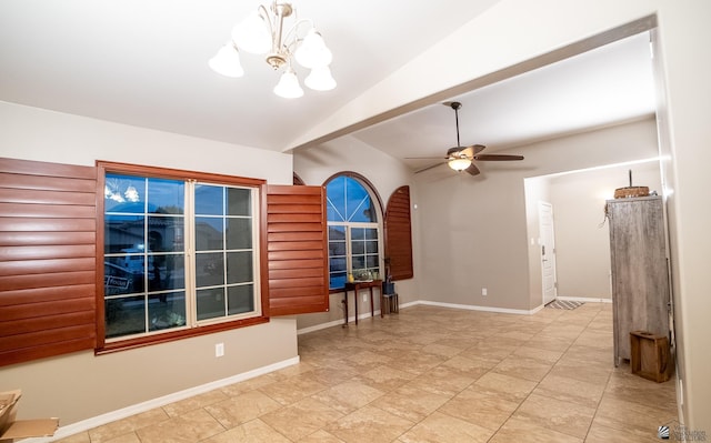 empty room featuring ceiling fan with notable chandelier, baseboards, and vaulted ceiling