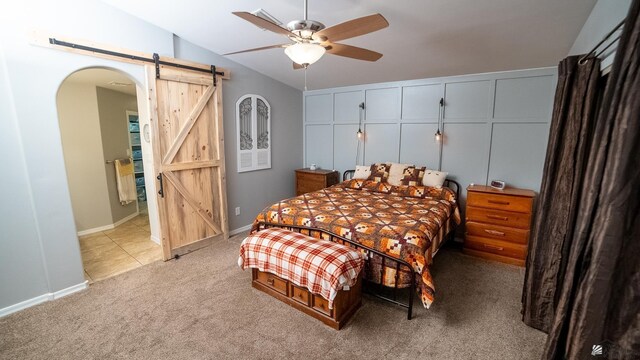 bedroom with a barn door, light carpet, arched walkways, baseboards, and vaulted ceiling