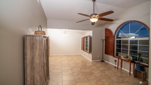 empty room with baseboards, lofted ceiling, and ceiling fan with notable chandelier