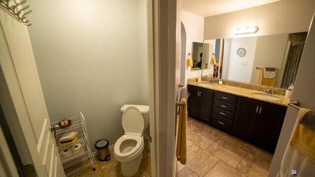 bathroom featuring double vanity, toilet, a sink, and tile patterned flooring