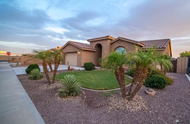 mediterranean / spanish-style house with driveway, a tile roof, a garage, fence, and stucco siding