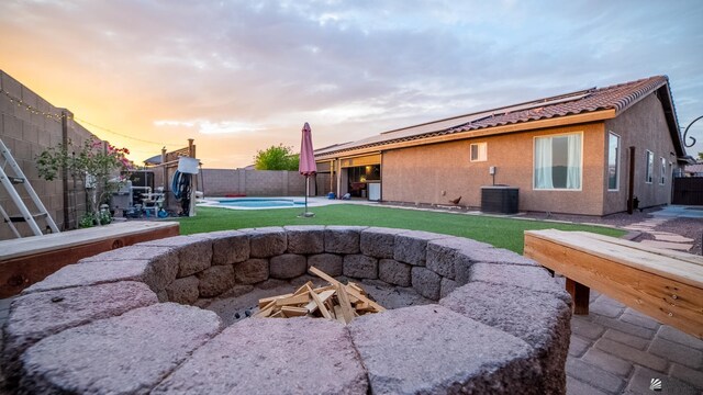 view of yard with central AC, a fenced backyard, a fenced in pool, a patio, and a fire pit