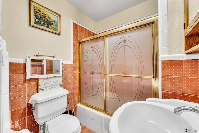 1802 S 11th Ave, Yuma, AZ 85364 - bathroom featuring tile walls, a sink, toilet, combined bath / shower with glass door, and a wainscoted wall