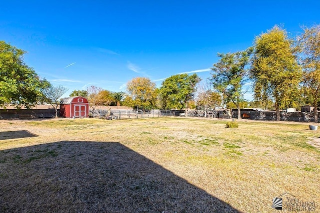 view of yard with a storage shed, fence, and an outdoor structure