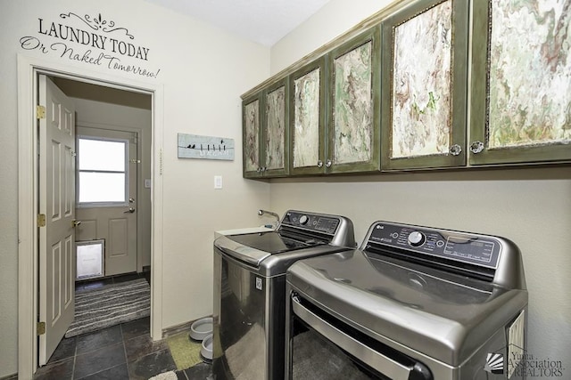 clothes washing area featuring cabinet space, washer and dryer, and stone finish floor