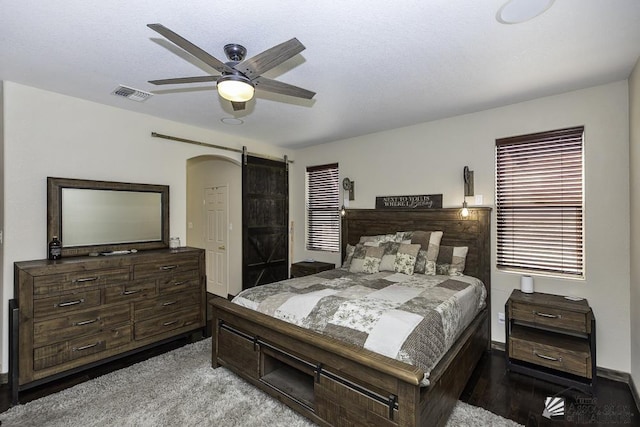 bedroom with a ceiling fan, a barn door, and visible vents