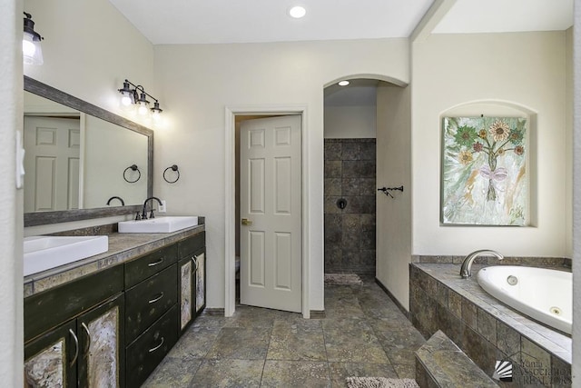 bathroom featuring walk in shower, a sink, double vanity, a bath, and stone tile flooring