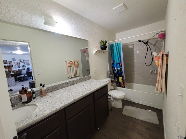 full bath featuring vanity, shower / tub combo with curtain, a textured wall, wood finished floors, and toilet
