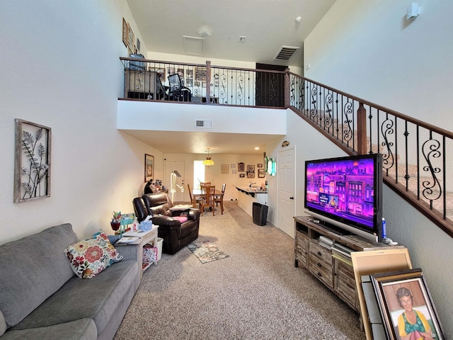living room featuring visible vents, carpet, and a towering ceiling