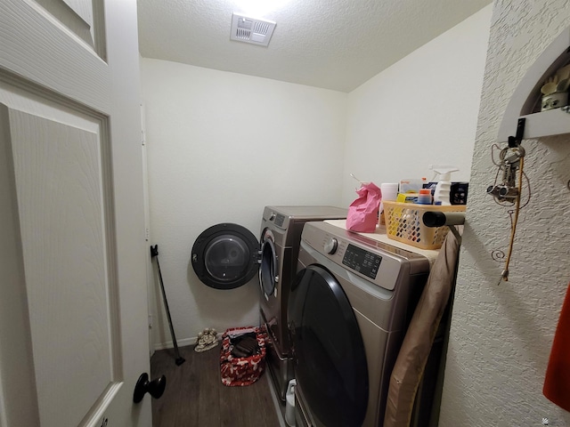 laundry area featuring visible vents, laundry area, wood finished floors, washer and dryer, and baseboards