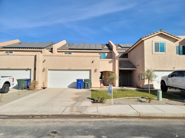 view of front of property featuring concrete driveway, stucco siding, a tiled roof, and solar panels