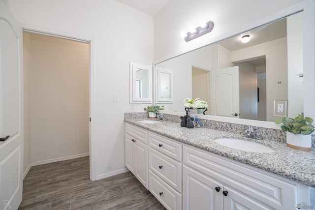 bathroom with double vanity, a sink, baseboards, and wood finished floors