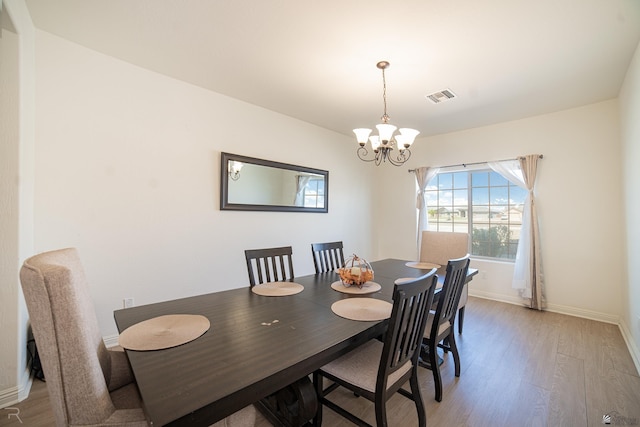 dining room with baseboards, light wood-type flooring, a chandelier, and visible vents