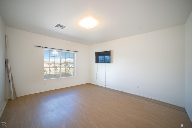 unfurnished room with baseboards, light wood-style flooring, and visible vents