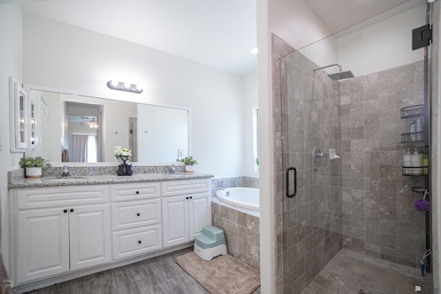 full bathroom with a sink, double vanity, a shower stall, wood finished floors, and a bath
