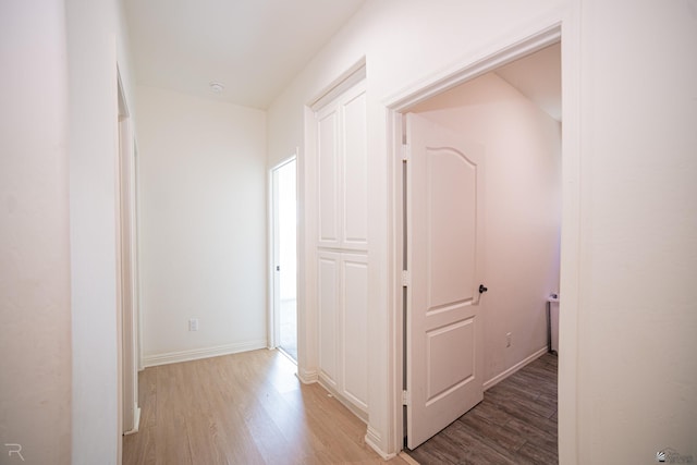 corridor with baseboards and light wood-style flooring