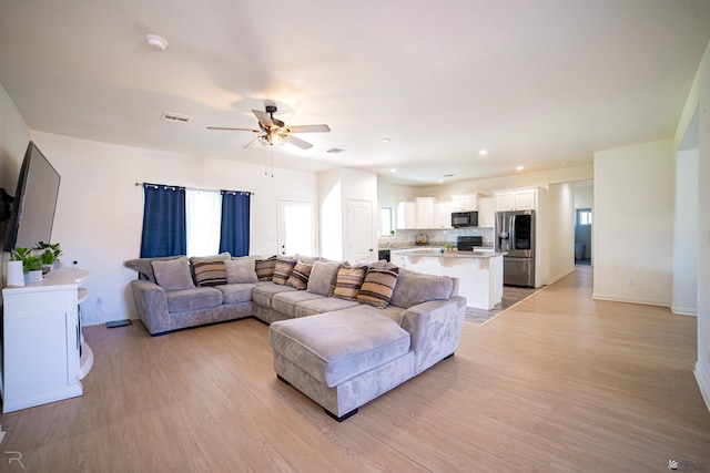 living room with visible vents, light wood-style floors, baseboards, ceiling fan, and recessed lighting
