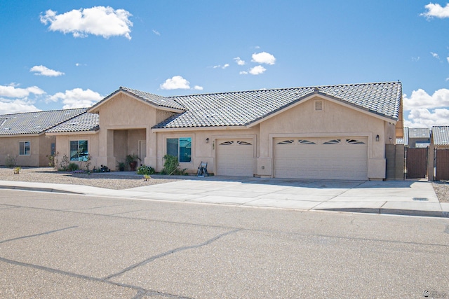 ranch-style home with fence, a garage, stucco siding, a tiled roof, and driveway