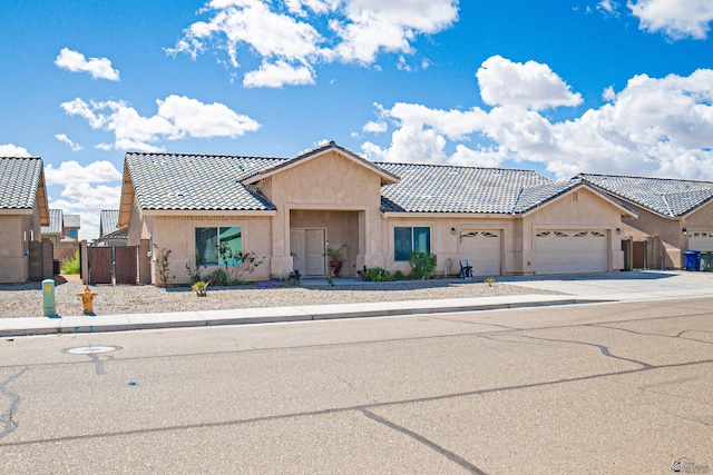 townhome / multi-family property featuring a garage, fence, stucco siding, a tiled roof, and concrete driveway