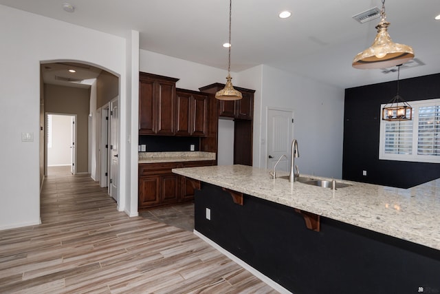 12839 S Drucilla Ln, Yuma, AZ 85367 - kitchen featuring a sink, arched walkways, a kitchen breakfast bar, hanging light fixtures, and dark brown cabinetry