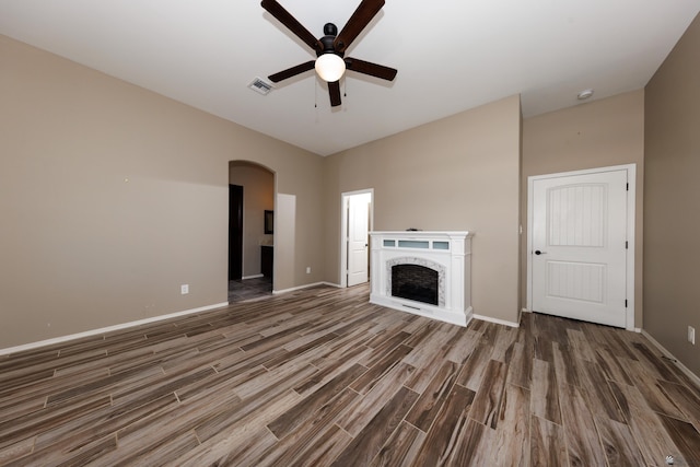 12839 S Drucilla Ln, Yuma, AZ 85367 - unfurnished living room with a ceiling fan, wood finished floors, arched walkways, baseboards, and a fireplace
