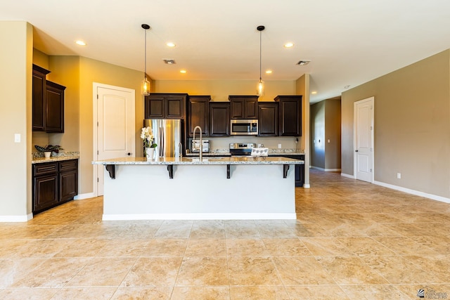 14817 E 47th Dr, Yuma, AZ 85367 - kitchen with appliances with stainless steel finishes, dark brown cabinetry, a kitchen bar, recessed lighting, and a spacious island