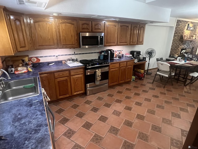 1911 S 11th Ave, Yuma, AZ 85364 - kitchen with appliances with stainless steel finishes, dark countertops, tasteful backsplash, a sink, and brown cabinetry